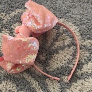 Large peach bow headband made of ribbon and has sequins detailing